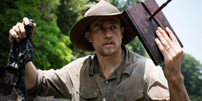 Percy Fawcett (holding a book with an arrow stuck through it) stands looking off screen to the right. This is a still from the film the lost city of z